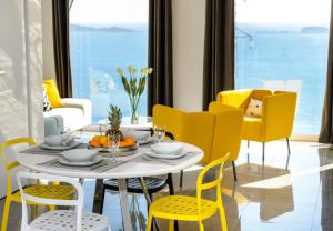 a dining room with a white table and yellow chairs at Apartments Villa Capitano in Mlini