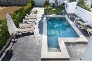 a swimming pool with chaise lounges and chairs in a backyard at Chalet Árbol de la Vida in Chiclana de la Frontera