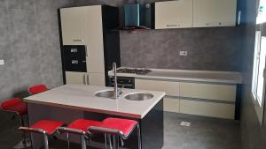 a kitchen with a sink and four red stools at Luxury Garden Villas Complex in Salalah