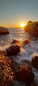 a sunset over the ocean with rocks in the water at Apartment Croatia Art in Drasnice