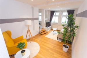 ein Wohnzimmer mit einem gelben Stuhl und Topfpflanzen in der Unterkunft FULL HOUSE Premium Apartments Halle City KU15 in Halle an der Saale