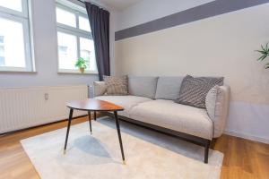 ein Wohnzimmer mit einem Sofa und einem Tisch in der Unterkunft FULL HOUSE Premium Apartments Halle City KU15 in Halle an der Saale