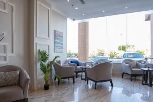 a waiting room with chairs and tables and windows at فندق كارم in Raḩīmah