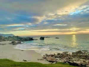 uma praia com rochas e o oceano ao pôr do sol em Whale Rock na Cidade do Cabo