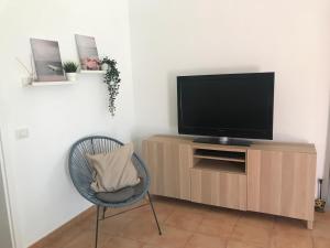 a living room with a chair and a flat screen tv at Casa Dylan in Puerto Calero