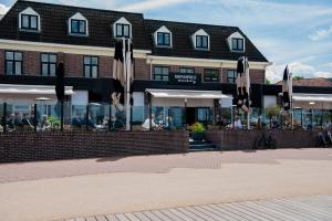un restaurant avec des parasols en face d'un bâtiment dans l'établissement Restaurant & Hotel Monopole Harderwijk, à Harderwijk