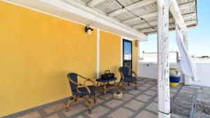 a patio with two chairs and a table and a yellow wall at Les Maisons La Mansardina by Rentbeat in Sannicola