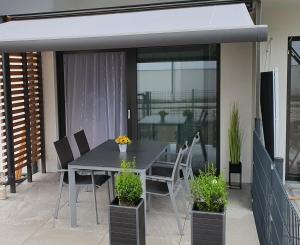 un patio con puertas de cristal, mesa de comedor y sillas en Luxuriöses Apartment mit Garten & Terrasse in der Nähe vom See im schönen Salzkammergut en Gmunden