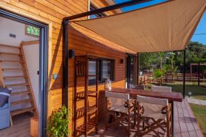 a deck with a wooden table and chairs and a wooden house at Nomade Caravan Camping in Fethiye