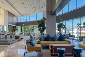 a lobby with a couch and chairs and windows at Amanta Hotel & Residence Sathorn in Bangkok