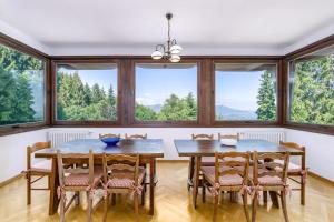uma sala de jantar com mesa e cadeiras e janelas grandes em Villa Nelma by Casa da Suite em Gignese