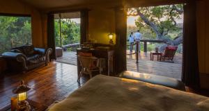a room with a bed and a large glass door with a deck at Serengeti Migration Camp in Serengeti National Park