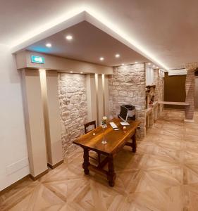 Habitación con mesa de madera y pared de piedra. en Affittacamere Residenza Montedoro, en Norcia