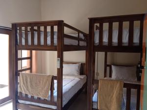 2 drewniane łóżka piętrowe w pokoju z oknem w obiekcie HAPPY PENIDA HOSTEL 2 w mieście Toyapakeh