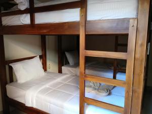 two bunk beds in a room with a white bed at HAPPY PENIDA HOSTEL 2 in Toyapakeh