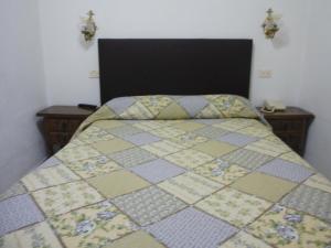 a bedroom with a bed with a quilt on it at Hotel Conde in Taboadela
