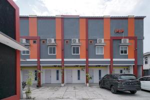 a gray and orange building with a car parked in front at Urbanview Hotel Pondok Indah Pringsewu By RedDoorz in Margakaya