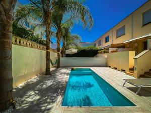 a swimming pool in front of a house with palm trees at Casa Molinar in Palma de Mallorca