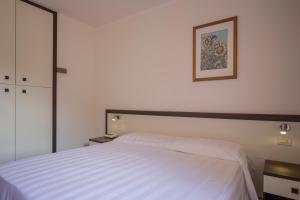 Un dormitorio con una cama blanca y una foto en la pared en Hotel Fabricia, en Portoferraio