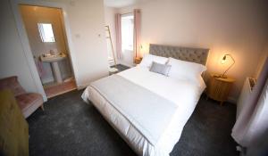 a bedroom with a large white bed and a sink at Tigh Beag Na Mara in Roag