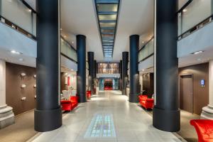 a lobby of a building with columns and red chairs at Martin's Patershof in Mechelen