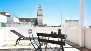 a table and chairs on a balcony with a clock tower at Les Maisons Casetta del Vico by Rentbeat in Sannicola