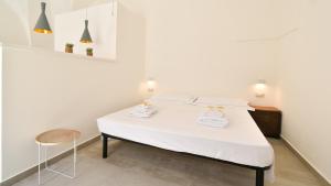 un letto bianco in una camera bianca con una sedia di Les Maisons Casetta del Vico by Rentbeat a Sannicola