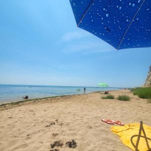 a blue umbrella on a sandy beach with the ocean at Ecopark Tuzlata Екопарк Тузлата in Balchik