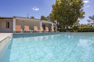 einen Pool mit Stühlen und ein Haus in der Unterkunft Villa Romeo 454 in Crestatx