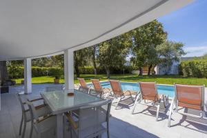 eine Terrasse mit Stühlen, einem Tisch und einem Pool in der Unterkunft Villa Romeo 454 in Crestatx