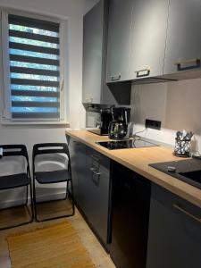 cocina con encimera y 2 taburetes en Alexander Cozy Apartment FREE PRIVATE PARKING, en Mediaş
