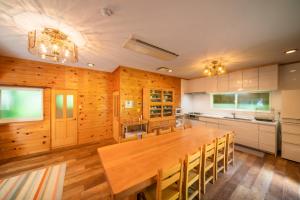 深山山荘 DENCHI في Uchiko: مطبخ كبير مع طاولة وكراسي خشبية كبيرة
