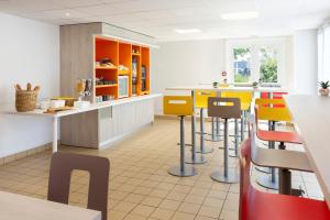 una cocina con taburetes amarillos y naranjas en un restaurante en Premiere Classe Nantes Ouest - St Herblain, en Saint-Herblain