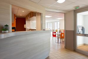 an office lobby with a reception counter and a table at Premiere Classe Nantes Ouest - St Herblain in Saint-Herblain