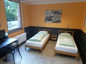 two beds in a room with a desk and a computer at Central Pension in Duisburg