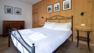a bedroom with a bed with white sheets and a table at Italianway - San Gallo 16 in Bormio