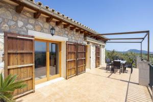 a patio with wooden doors and a table and chairs at Es Puchet in Búger +22 photos