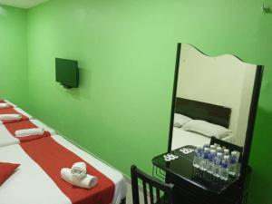 a green room with a bed and a mirror at EZI HOTEL KLANG in Klang