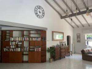 a living room with a book shelf and a clock at Belle Villa basque avec piscine et jardin de 3000m2 in Saint-Jean-de-Luz