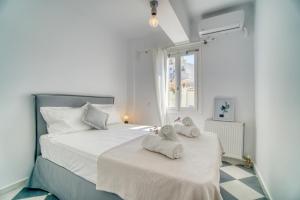 a white bedroom with two towels on a bed at Stylish, Cozy 2-BDR Flat in Andros Town in Andros