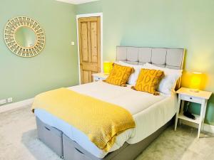 a bedroom with a bed with yellow pillows and a mirror at Ilkley Cottage in Ilkley
