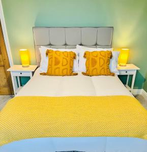 a large bed with yellow pillows and two tables at Ilkley Cottage in Ilkley