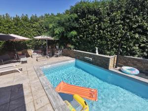 a swimming pool with a chair and a swimming pool at Indè Noi - Maison de village proche commodités in Murato
