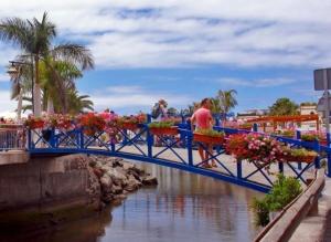 a man walking over a blue bridge with flowers at First Line Luxury Apartment by El Sirocco in Puerto de Mogán