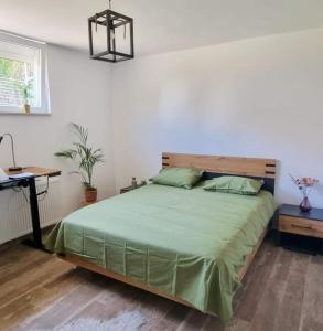 a bedroom with a bed with a green comforter and a desk at Enjoy a private room in the center of Antwerpen in Antwerp
