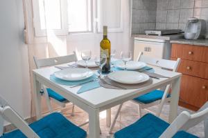 a white table with two plates and a bottle of wine at A & K Vacation House in Varos