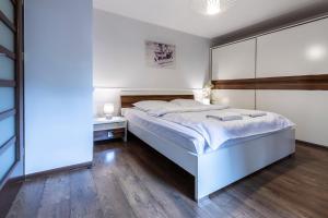 1 dormitorio con 1 cama blanca grande y suelo de madera en TatryTOP Tetmajer Centrum, en Zakopane