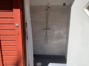 La salle de bains est pourvue d'une douche et d'un mur en métal. dans l'établissement Nissevikens Stugby, à Havdhem