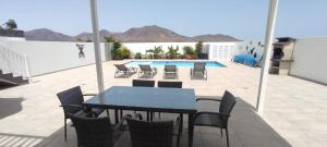 eine Terrasse mit einem Tisch, Stühlen und einem Pool in der Unterkunft Villa Carol in Playa Blanca