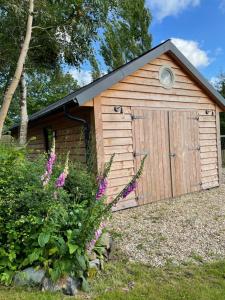 a wooden shed with a door in a yard at The Potting Shed in St Austell